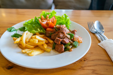 Plate of tasty stir-fried beef and vegetables with french fries 