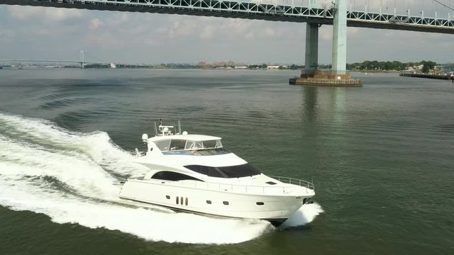 Tracking luxury yacht while panning up and revealing Throgs Neck bridge, beautiful 4k footage