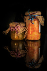 two small glass jars of homemade jam with rustic decoration