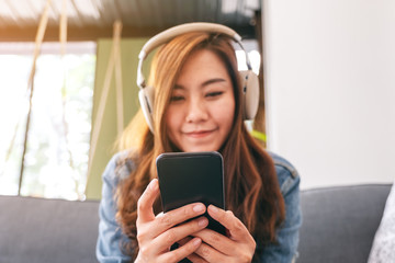 Fototapeta premium A beautiful asian woman using mobile phone and headphone to listen to music