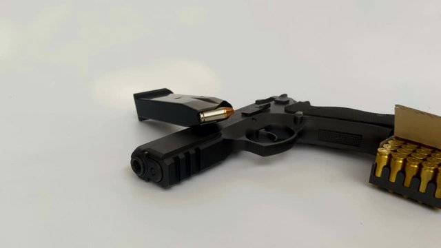 Shot of full-size black pistol with a box of 9mm ammunition on the side and magazine loaded with a hollow-point bullet on the white background in 4K.