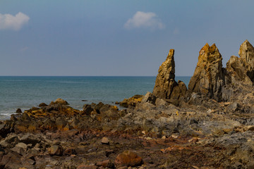 Big rocks on the shore in India with blue sea and mist on the ocean. Natural landscape of dark day.Summer travel concept.