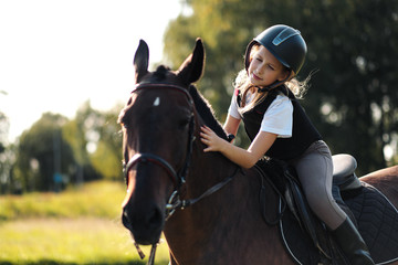 Obraz premium Girl teenager jockey sits on a brown horse, hugs and strokes her.