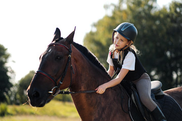 Obraz premium Girl teenager jockey sits on a brown horse, hugs and strokes her.