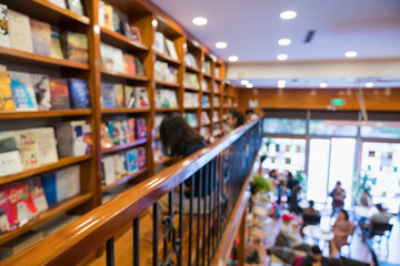 Blurred abstract background of bookshelves in book store, with a girl reading book in the store.
