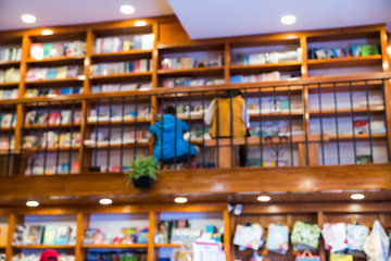 Blurred abstract background of bookshelves in book store, with people finding book in the store.