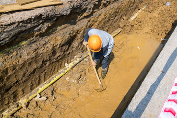 Worker working in ditch for sewage system in the city in Asia