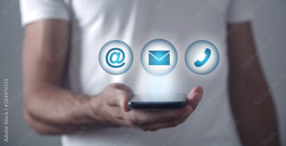 Wall mural man holding smartphone with contact symbols.