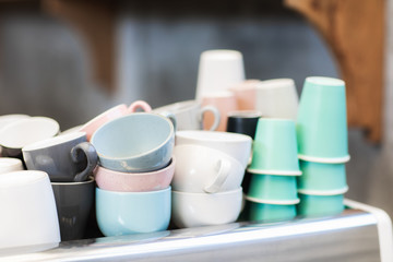 Heap of different blue, pink, white and green cups on coffee machine in cafe. Barista concept. Background of trendy hipster cafe.