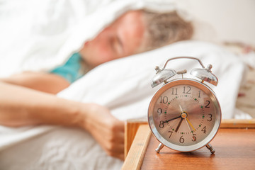 Young sleeping woman and alarm clock