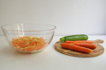 Carrot and pumpkin on the wooden cutting board. Grated vegetables in transparent bowl