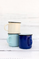 Enameled mugs in retro style on an old wooden background.