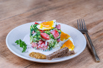 Delicious salad with broccoli, tomato, onion and boiled egg with cream sauce in plate on wooden background. Healthy food