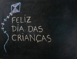 Blackboard written Feliz dia das criancas (Portuguese). Kite Drawing. Copy space.