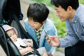 Obraz premium ベビーカーに乗る赤ちゃんの様子を撮影する父親