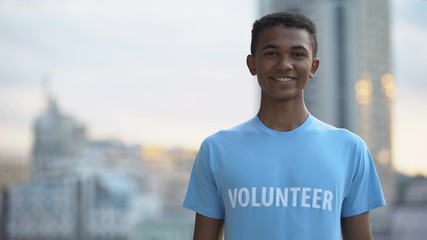 Joyful afro-american teenager volunteer t-shirt smiling camera, donation project