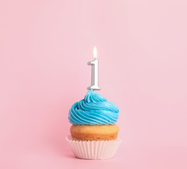 Birthday cupcake with number one candle on pink background