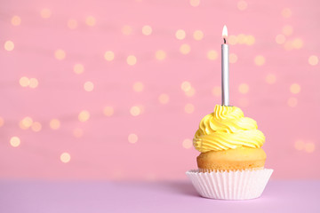Birthday cupcake with candle on table against festive lights, space for text