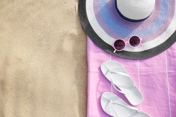 Flat lay composition of beach objects and towel on sand, space for text
