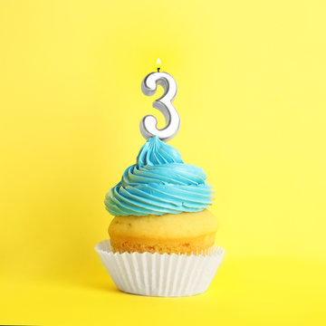 Birthday cupcake with number three candle on yellow background