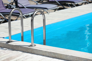 Modern swimming pool with step ladder outdoors
