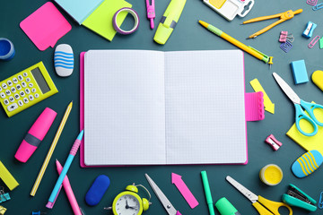 Different bright school stationery and blank notebook on green background, flat lay. Space for text