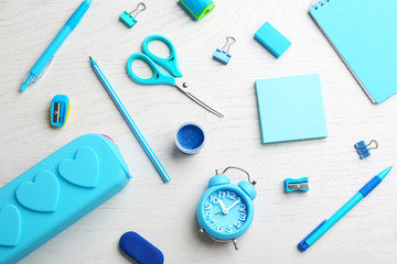 Different bright school stationery on white wooden background, flat lay