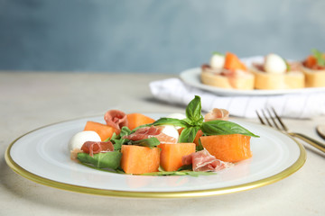 Fresh melon with prosciutto, mozzarella and basil on table