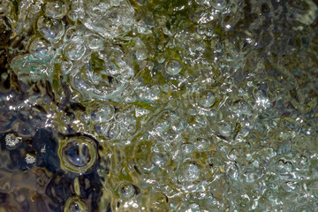 Background of greenish transparent water with air bubbles on the surface.