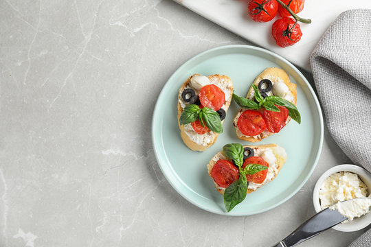 Plate of delicious tomato bruschettas on light grey marble background, flat lay. Space for text
