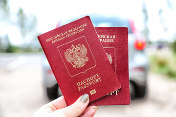 Russian passports in the hand of woman and car background
