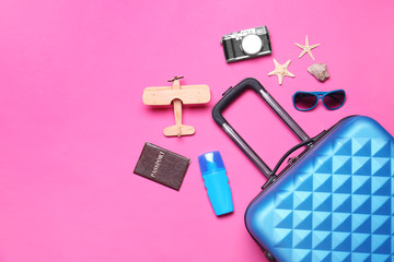 Flat lay composition with suitcase and beach objects on pink background. Space for text