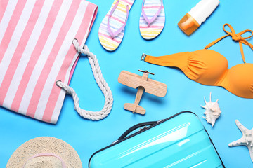 Flat lay composition with suitcase and beach objects on blue background