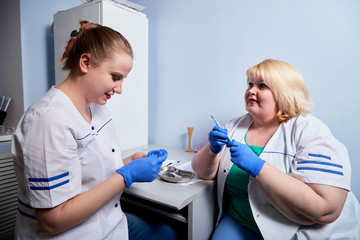 Experienced doctor fat woman and aspiring young doctor sittins at the table and discussing the medical problems