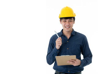Portrait of smiling young engineer in yellow helmet writing and holding checklist paper clipboard isolated on white background with copy space.