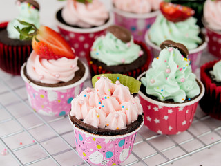 Fruit sliced decorated on chocolate cup cakes on marble table.