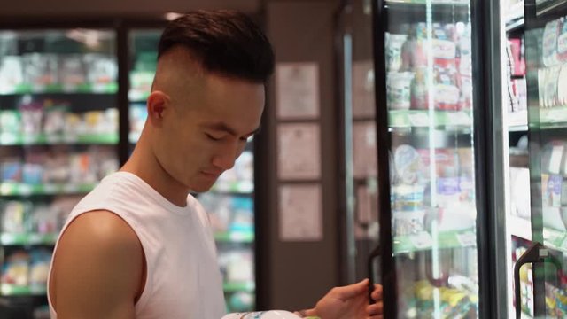Asian Man shopping at supermarket, steadicam shot. Young male goes among shelves with goods in grocery store. Concept daily purchase, product, consumer, people, mall, food