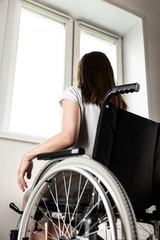 Fototapeta na wymiar Invalid or disabled woman sitting wheelchair looking window daylight