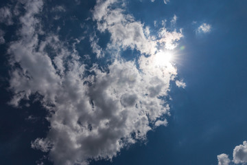 Naklejka na ściany i meble Blue sky with white clouds and sun. Sunny background.