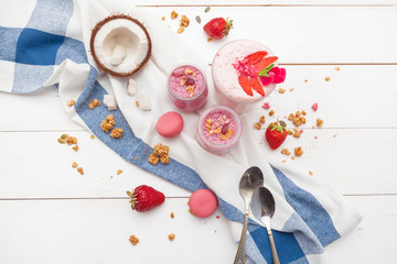 Healthy breakfast with yoghurt, granola and strawberries on white wooden background top view
