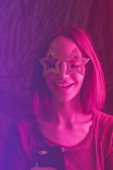 Girl neon light, dressed in glasses for party in form of stars, takes selfie on the phone.