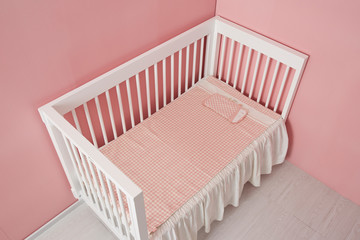White children's bed with a plaid mat and pillow