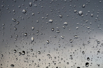beautiful raindrops on the glass through which you can see the stormy gray sky