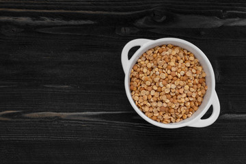 cereal dry peas in white bowl on dark wooden desk surface