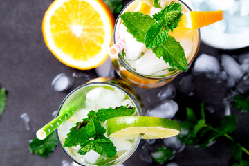 Mohito lime and orange drinks on black background.