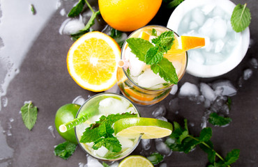 Mohito lime and orange drinks on black background.