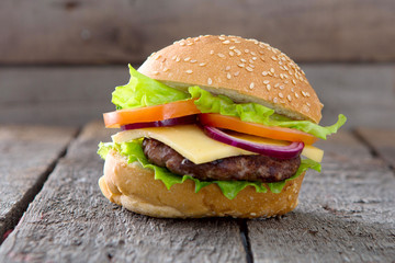 Delicious hamburger with fresh vegetables on wooden table.