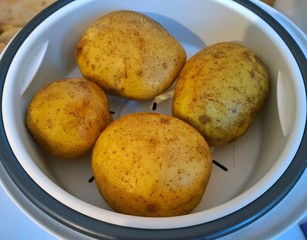Steaming potatoes in a slow cooker. Rich new harvest and food safety Concept. Organic healthy eating. Prepare kitchen and feed for Brexit. Economical cheap breakfast lunch or dinner.