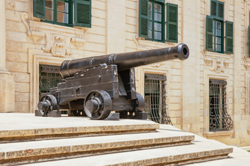 Fototapeta na wymiar Old ship cast iron gun in front of the building of Sandstone