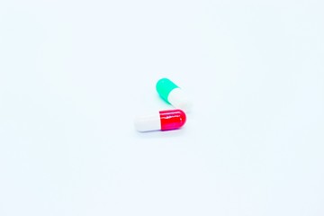 Multi-colored pill capsules are located on a white background
